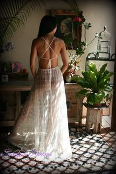 a woman standing in front of a painting wearing a white dress with sheer fabric on it