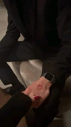 a man in black suit and red nail polish holding his cell phone