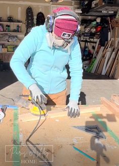 a woman is working on some wood in her workshop with a circular saw and other tools