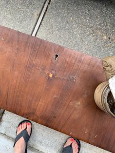 a person standing next to a skateboard on top of a cement slab with their feet propped up