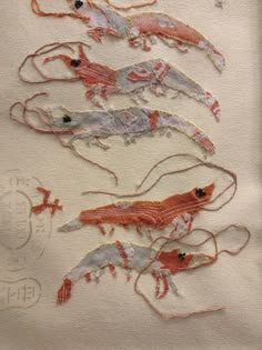 some very pretty embroidered animals on a piece of paper with thread in the shape of lizards