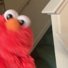 a close up of a person wearing a red sesame character costume and holding an orange object in their hand