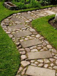 a stone path in the middle of some grass