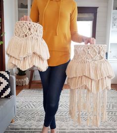 a woman is holding two purses in her hands and standing next to a couch