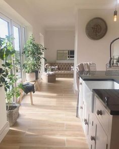 a living room filled with furniture next to a window covered in lots of green plants