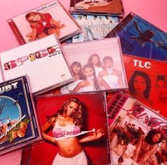 various cd's are stacked on top of each other in a pile with pink background