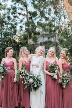 a group of women standing next to each other wearing dresses and holding bouquets in their hands