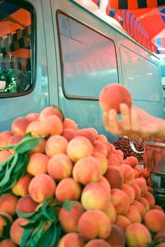 a person reaching for a donut in front of a truck filled with peaches