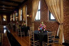 tables and chairs are set up in front of the brick wall, along with black tablecloths