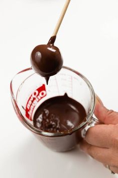 a hand holding a spoon with melted chocolate in it