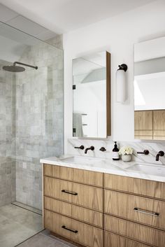 a bathroom with two sinks and a large mirror above the sink is next to a walk in shower