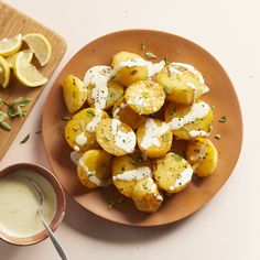 there is a plate of potato salad and a bowl of ranch dressing next to it