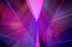 the inside of a building with purple lights and lines on it's sides,