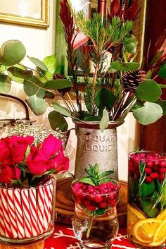 flowers and greenery are arranged in vases on a table