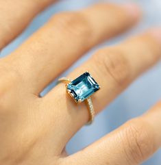 a woman's hand with a ring on it and a blue stone in the middle