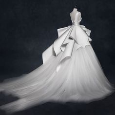 a white wedding dress on display in front of a black background