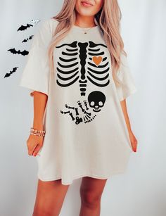 a woman wearing a skeleton t - shirt dress with bats flying around her and the words love is in the air