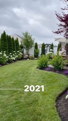 a lawn with flowers and trees in the background