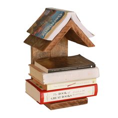 a stack of books sitting on top of each other next to a wooden bird house