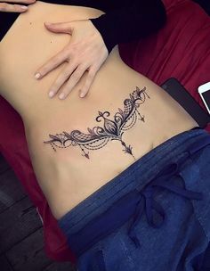 a woman's stomach with an intricate tattoo design on her lower side ribcage