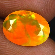 a person holding an orange opal in their hand