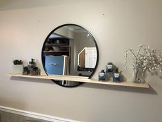 there is a mirror on the wall above a shelf