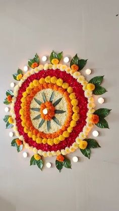 a clock made out of flowers and candles on the wall with lights in the background