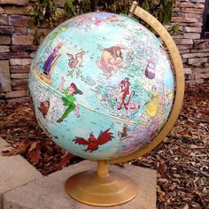 a globe with cartoon characters on it sits in front of a brick wall and tree