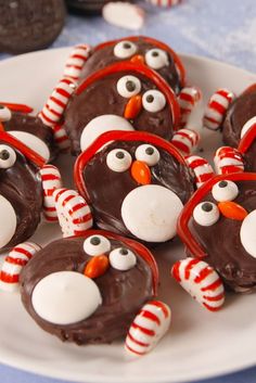 chocolate penguins with candy candies on a white plate and cookies in the shape of santa's hats