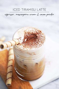 an iced drink with whipped cream and chocolate sprinkles on the top is sitting on a cutting board