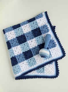 a blue and white crocheted blanket with two balls on it next to a pair of slippers