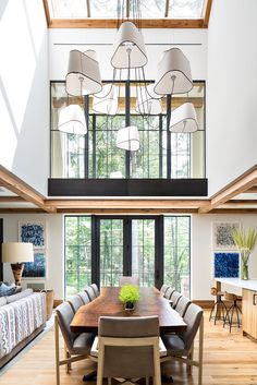 a dining room table and chairs in front of a large window with an open floor plan