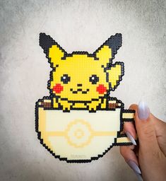 a person holding up a pixelated image of a pikachu in a cup