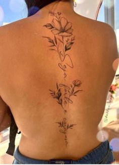 the back of a woman's tattoo with flowers on her upper and lower back