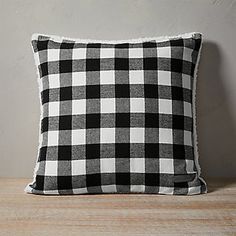 a black and white plaid pillow sitting on top of a wooden table