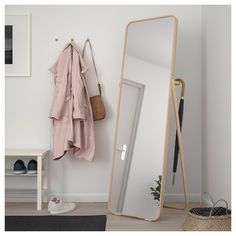 a mirror sitting on top of a wooden floor next to a coat rack