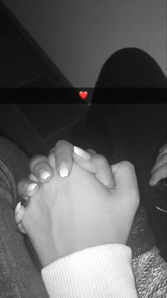 two hands holding each other with a red heart in the middle and black and white background