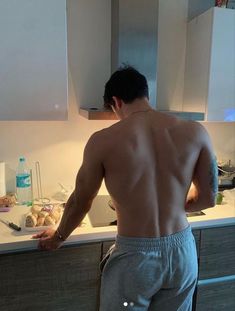 a shirtless man standing in front of a kitchen counter