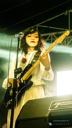 a woman playing an electric guitar on stage