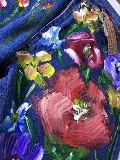 an artistically painted jean jacket with flowers on it