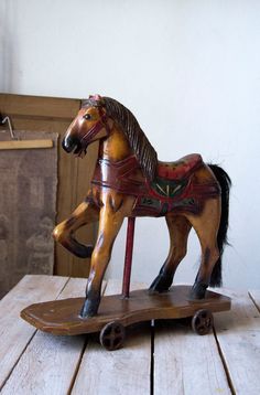 a wooden toy horse sitting on top of a skateboard