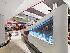 the interior of an airport with red and blue lights on the wall, luggage carousels in the background