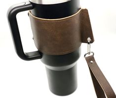 a coffee cup with a leather strap attached to it