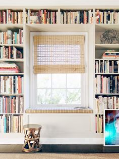 a window seat in front of a bookshelf filled with books