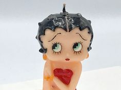 a little figurine that is sitting on the ground with a heart in it's mouth