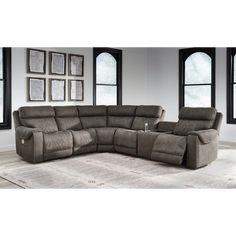 a large sectional couch with recliners in front of two windows and a rug on the floor