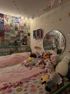 a bedroom with many stuffed animals on the bed and in front of a round mirror