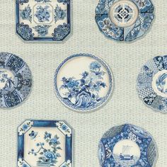 blue and white plates with floral designs are arranged on a wallpapered surface,