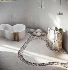 a white bath tub sitting next to a stone floor in a room with rocks on the ground