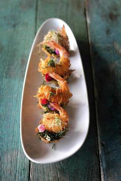 a white plate topped with sushi on top of a wooden table next to a knife